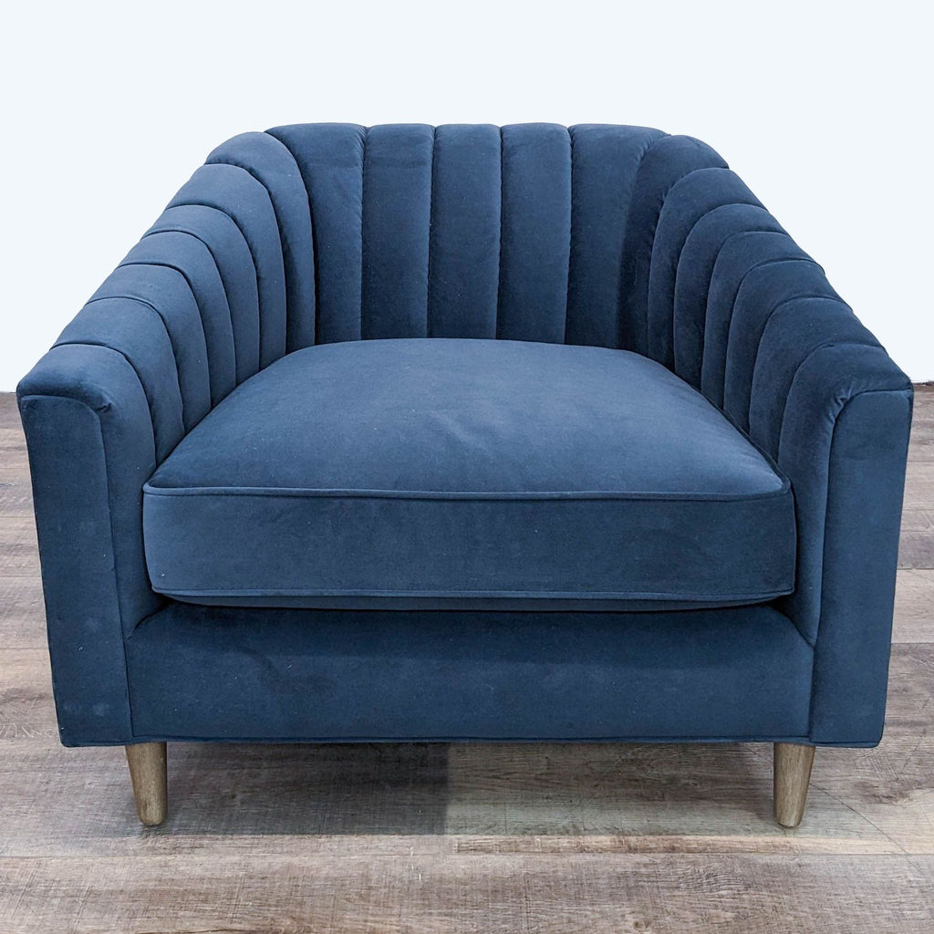 Diagonal angle showing the tufted barrel back and seat cushion of a Four Hands blue velvet lounge chair.