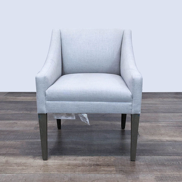 Light grey upholstered accent chair by The Brownstone with sloped arms and dark wood legs, modern style.