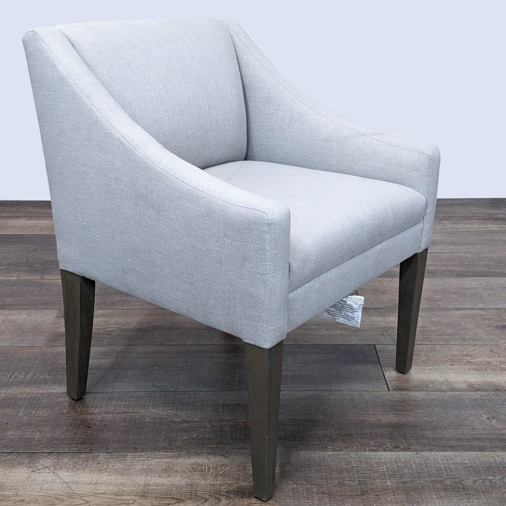 Grey textile lounge chair with sloping armrests and dark tapered legs from The Brownstone, frontal view.
