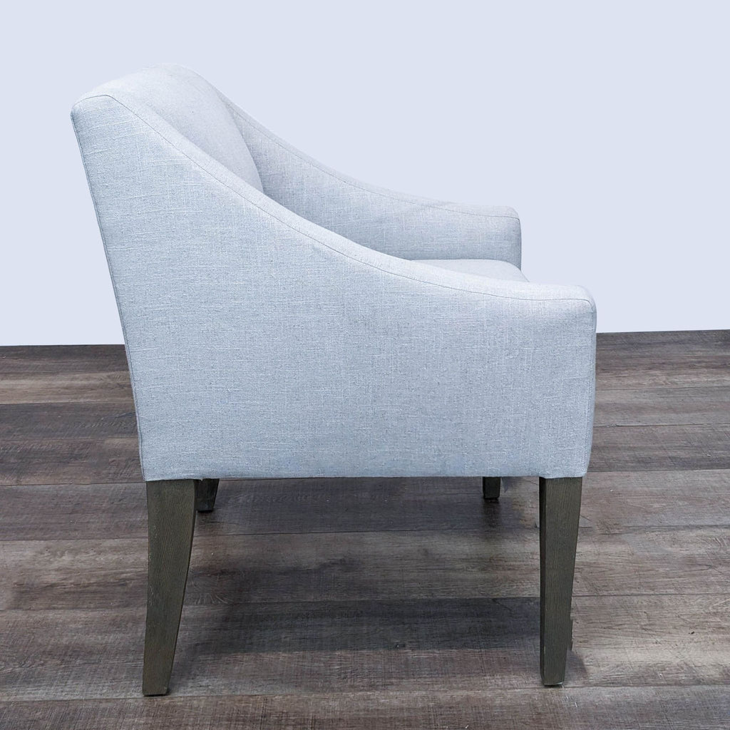 The Brownstone brand's modern lounge chair featuring light grey fabric and elegantly tapered wooden legs.