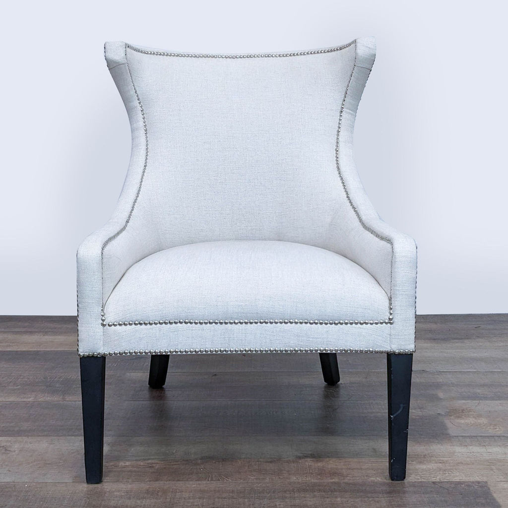Reperch high-backed lounge chair with white upholstery and silver nailhead detailing, on wooden legs.