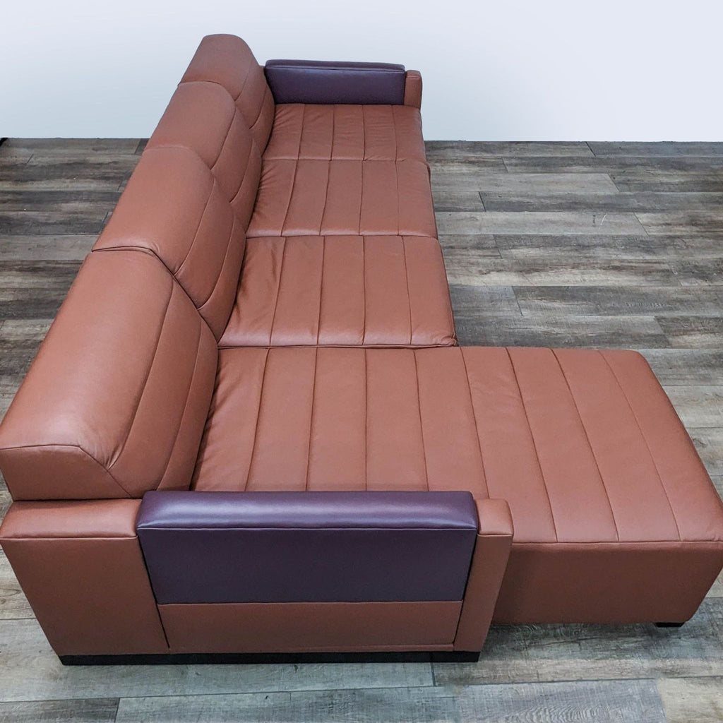 2. Side view of a Reperch brand brown leather sectional, highlighting the chaise and cushioning comfort on a wood-patterned floor.