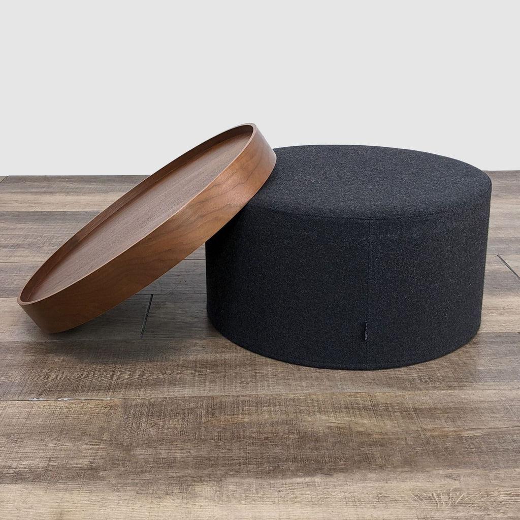 2. Round wooden tray lifted off its dark fabric base, part of a Design within Reach coffee table.