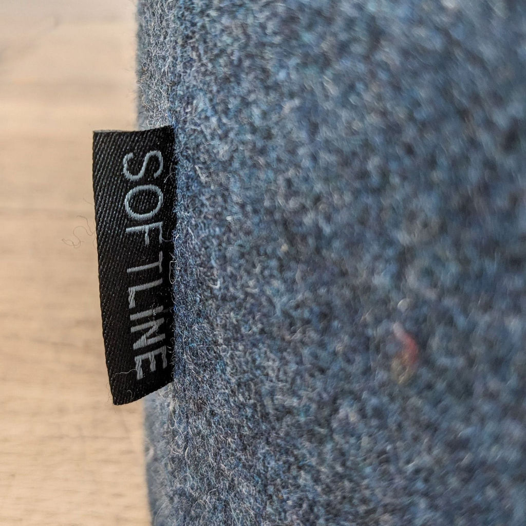 3. Close-up of a blue fabric tag on the side of the coffee table's base with the text "SOFTLINE".