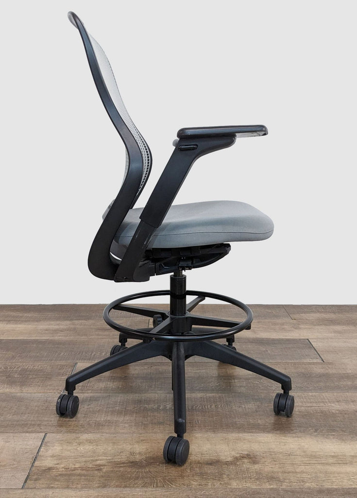 Side view of a modern Knoll swivel chair with ergonomic design, adjustable armrests and casters on wooden floor.