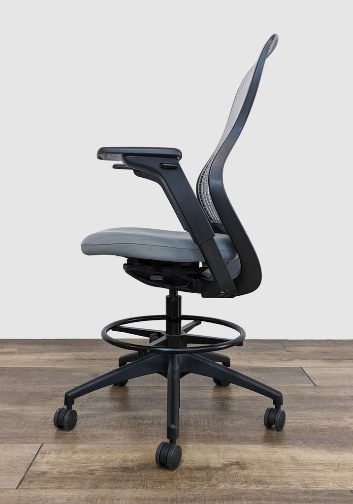 Knoll adjustable desk chair showcasing its profile with flexible back support and armrests, set on a wooden floor.