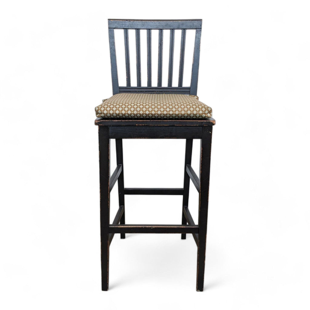Crate and Barrel solid wood barstool with distressed black paint and a beige-patterned removable cushion.