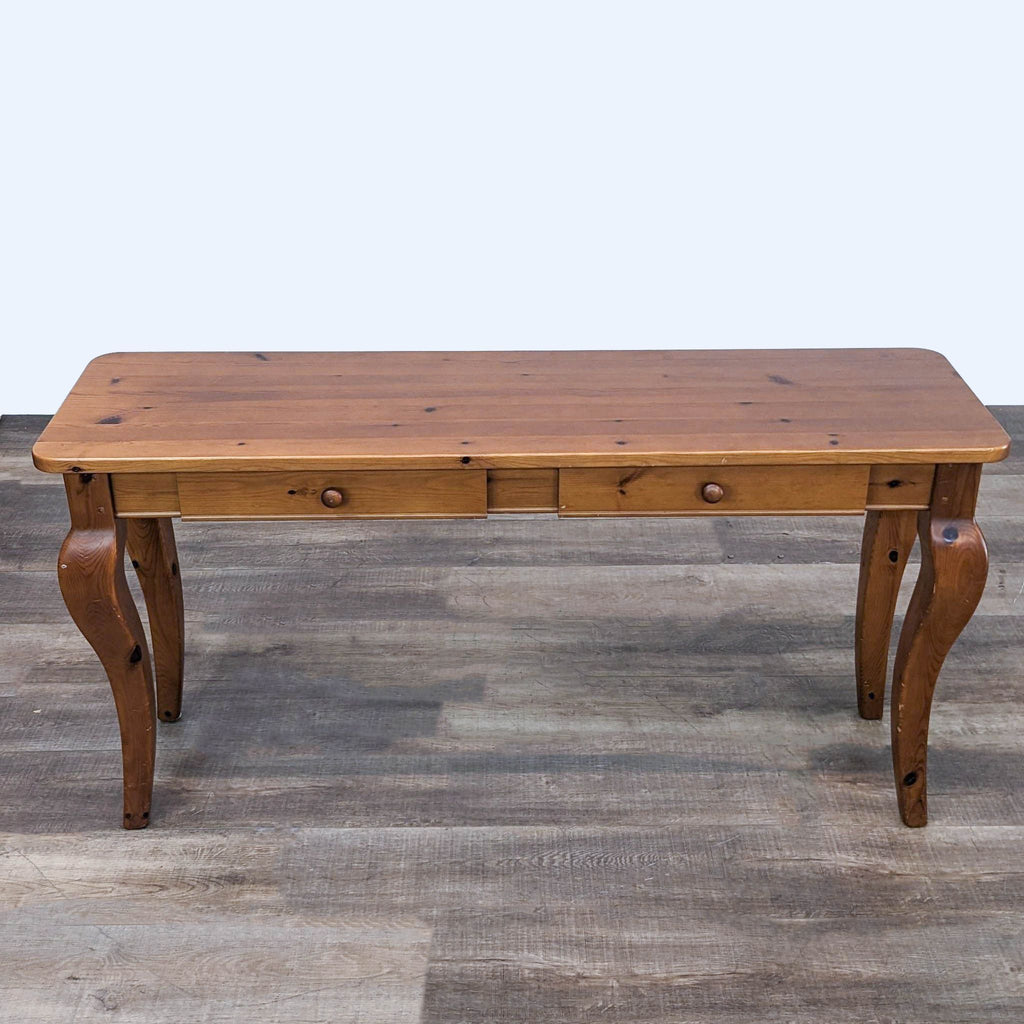 Wooden two-drawer Pottery Barn table, showing top and cabriole legs, against a neutral backdrop.