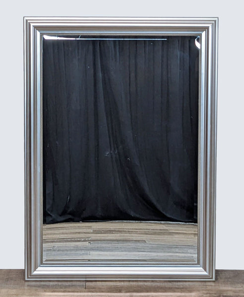 a large silver framed mirror with a black curtain behind it.