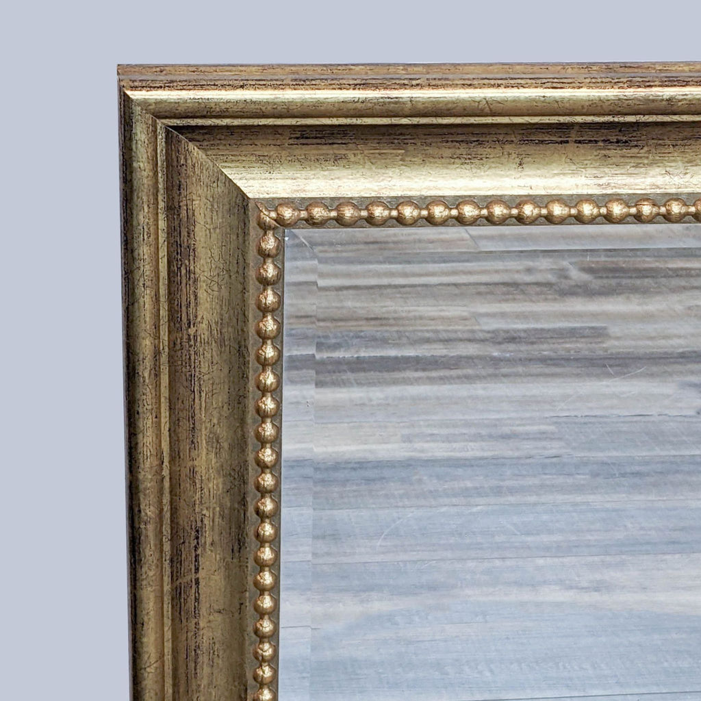 Close-up of Reperch mirror's gold-finish frame and beaded inner edge detail.