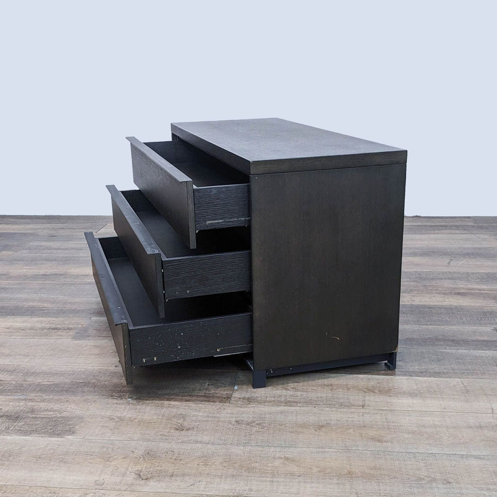 Three open drawers of a Reperch contemporary black dresser showing storage space.