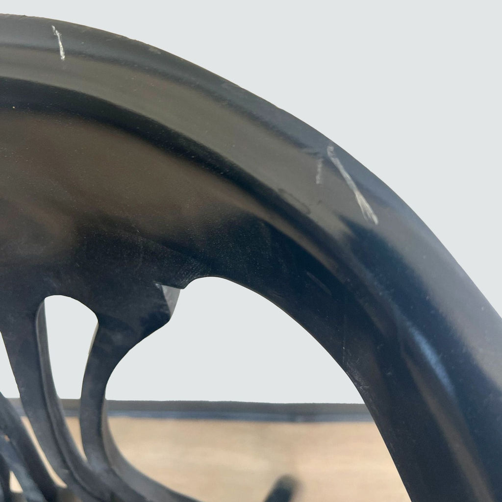 Close-up of a Reperch dining chair's curved backrest detailing and black lacquer finish with visible wear marks.