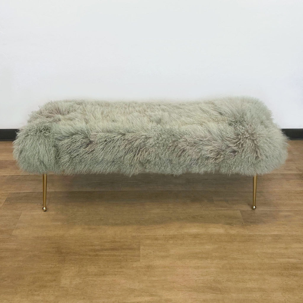1. Gray shaggy fur bench from H.D. Buttercup with sleek gold-tone legs, displayed on a hardwood floor against a white wall.