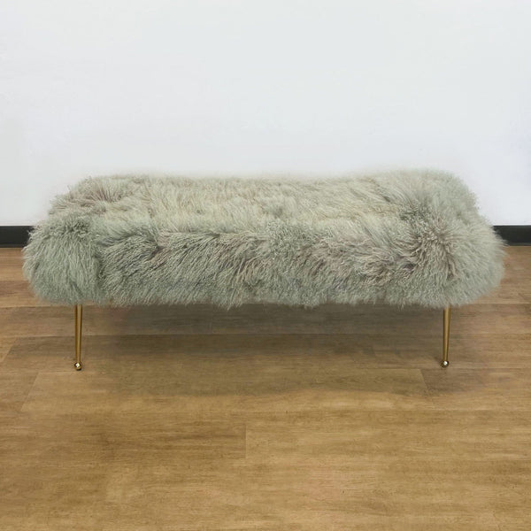 1. Gray shaggy fur bench from H.D. Buttercup with sleek gold-tone legs, displayed on a hardwood floor against a white wall.