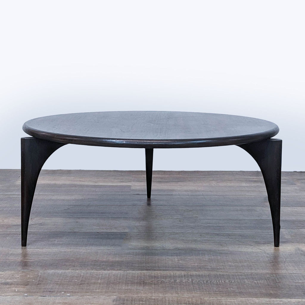 Round Brownstone Furniture coffee table on a wooden floor, dark finish, minimalistic design.