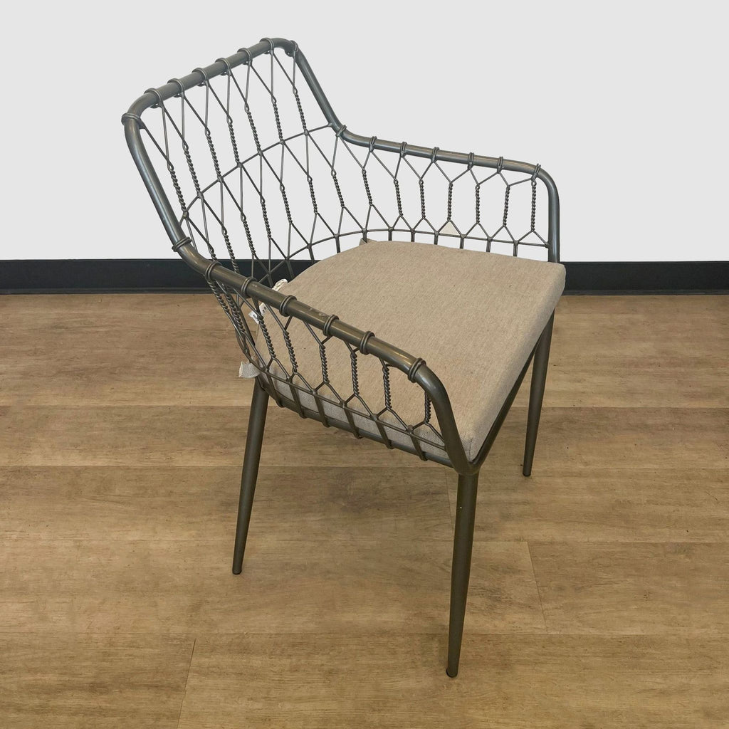 Modern Reperch dining chair with a unique intertwined metal backrest and beige seat cushion on a wooden floor.