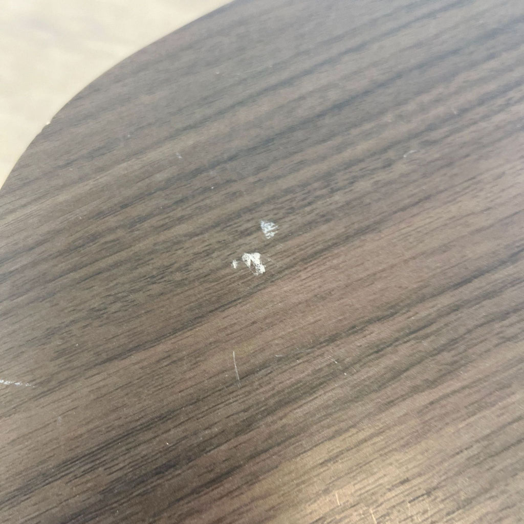 3. "Close-up of a wooden table surface showing minor damage with white marks on the veneer."