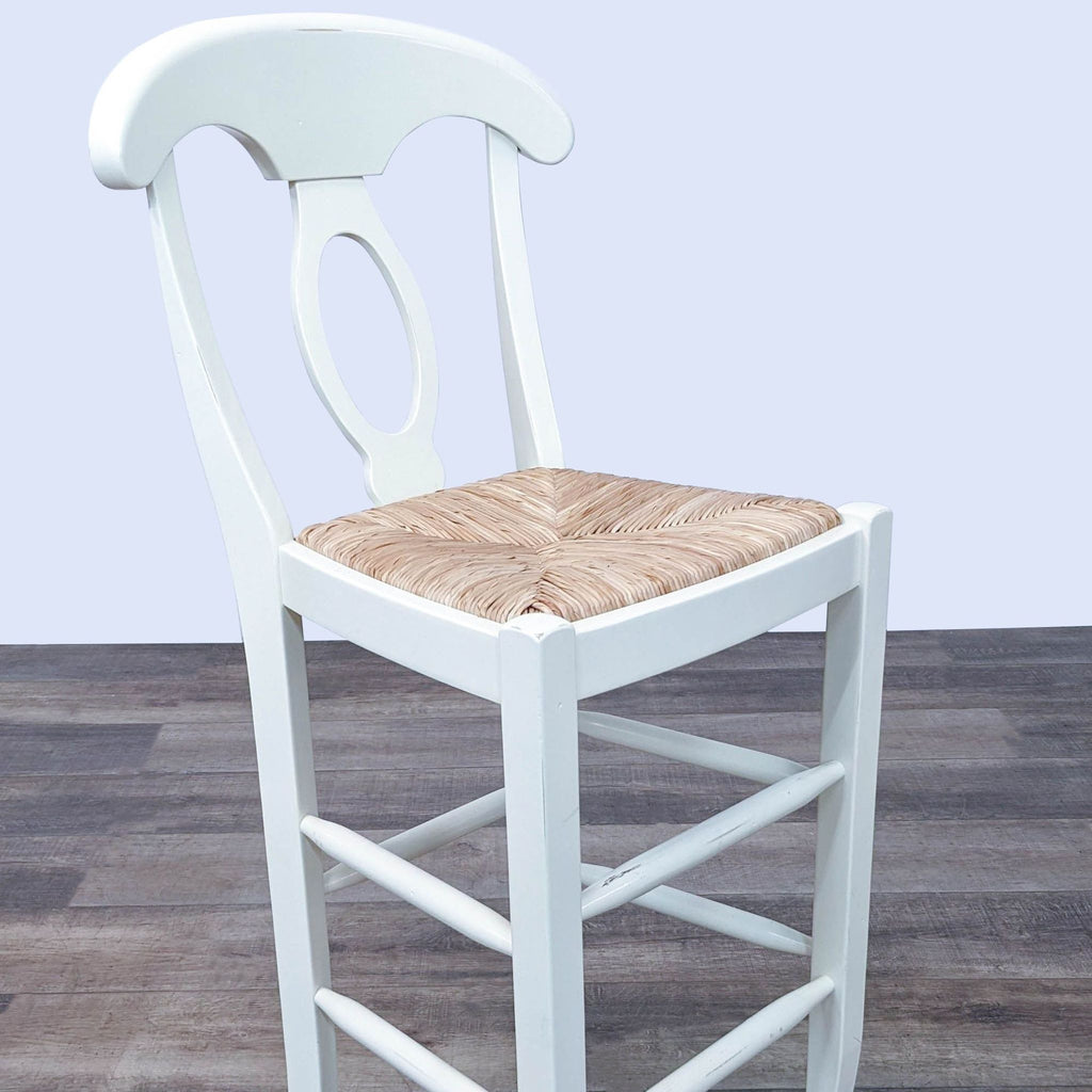 2. Single ivory wooden barstool showcasing its curved backrest, oval detail, and woven rush seat.