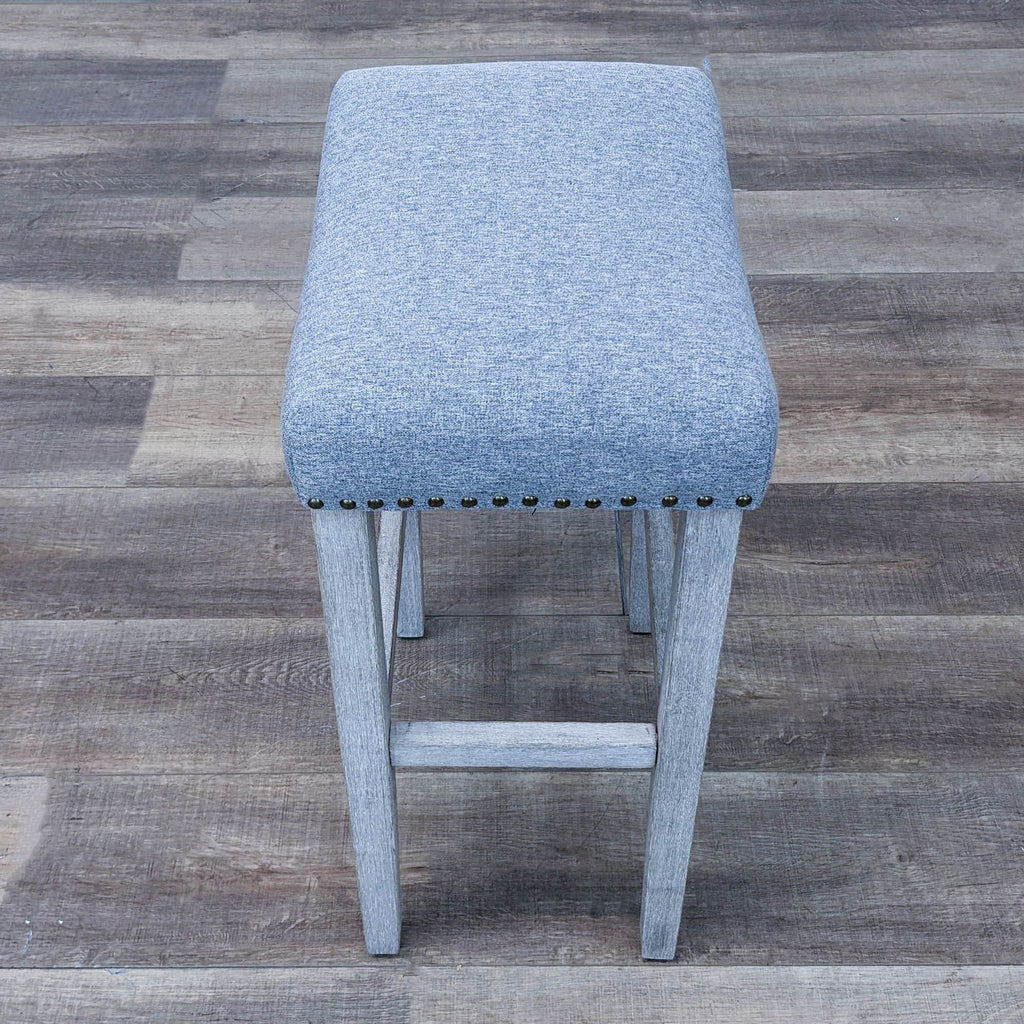 Front view of Reperch's padded barstool in gray with nailhead accents.