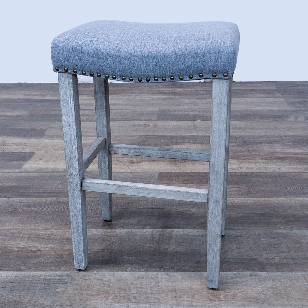 Reperch barstool featuring gray upholstery and nailhead trim, angled side view.