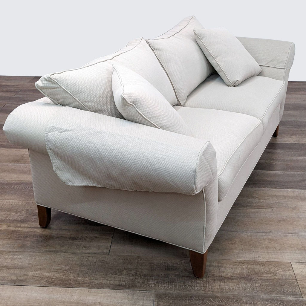 a white leather sofa with four pillows.