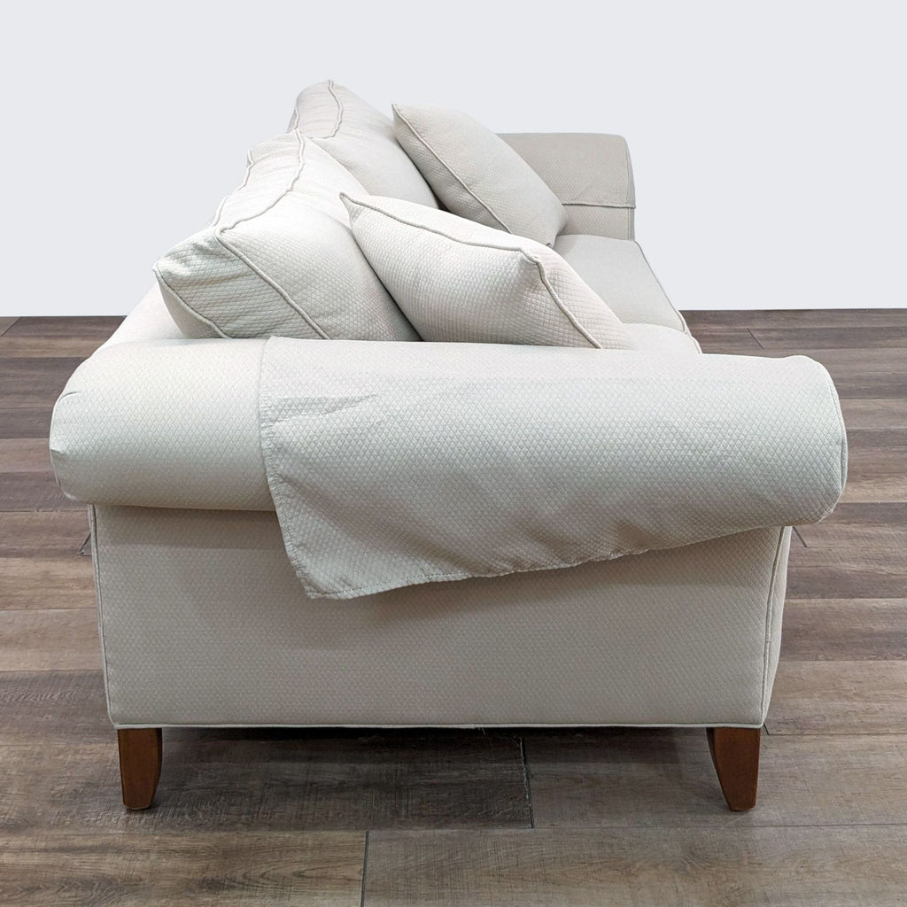 a cream colored sofa with a white fabric cover and a matching pillow.