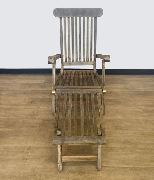 Foldable gray teak lounge chair with adjustable backrest on a wooden floor.  