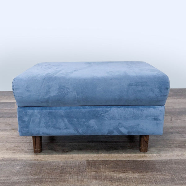 a blue velvet footstool with a wooden base.