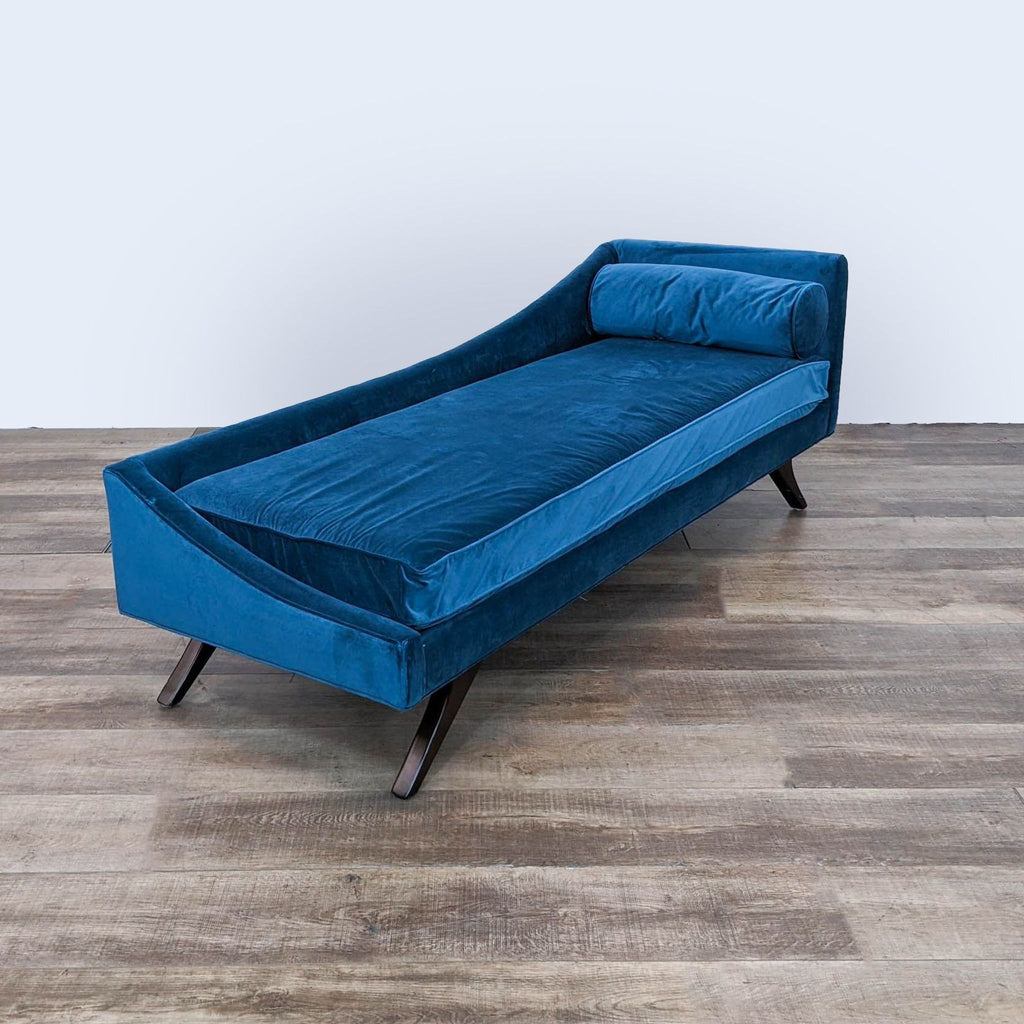 a blue velvet chaise lounge with a black metal base.