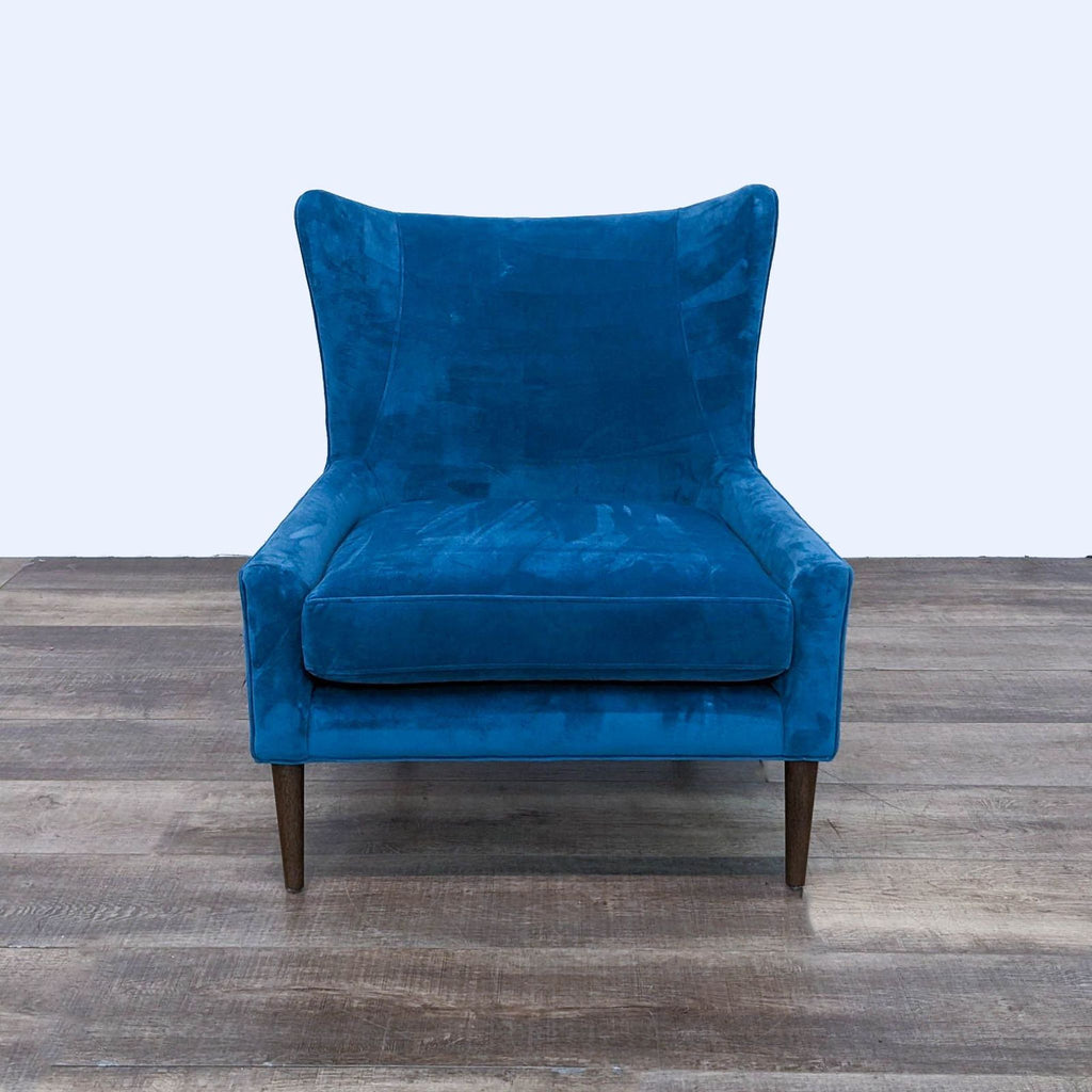 Front view of a Four Hands Marlow blue velvet wingback chair with tapered wood legs, lounge category.  