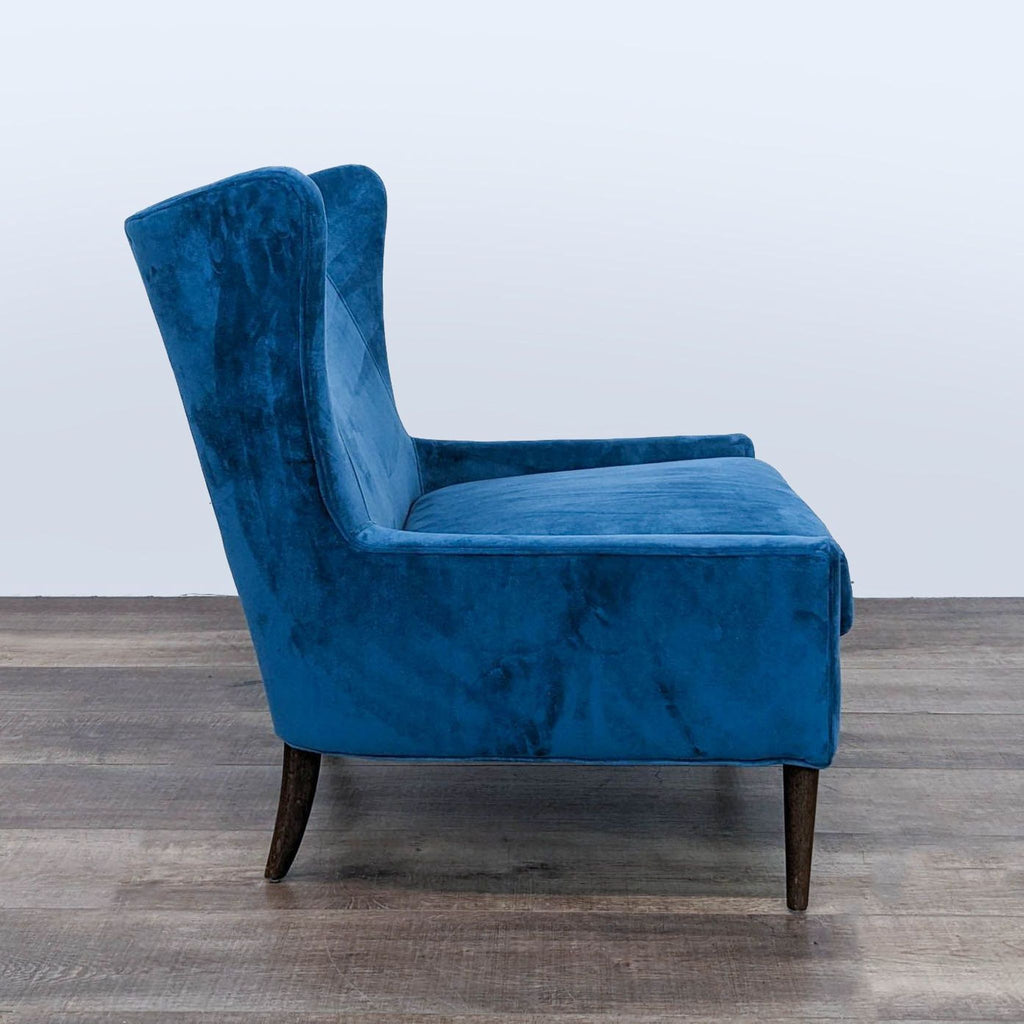Side view of Four Hands Marlow lounge chair in blue velvet upholstery, featuring sleek tapered wood legs.  