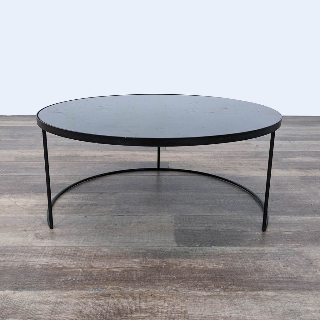 Notre Monde coffee table featuring a round aged mirror top on sleek metal legs.