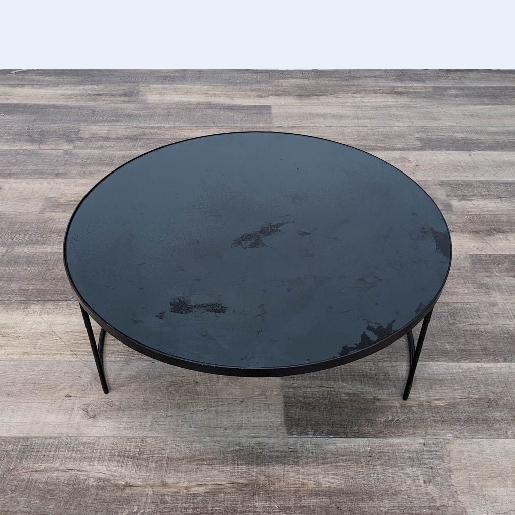 Top-down view of a Notre Monde round coffee table with a distressed mirror surface and metal base.