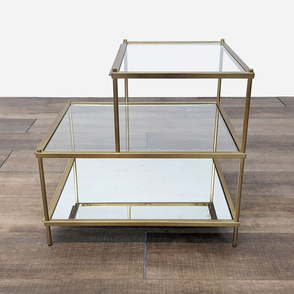 a pair of brass side tables with glass shelves.