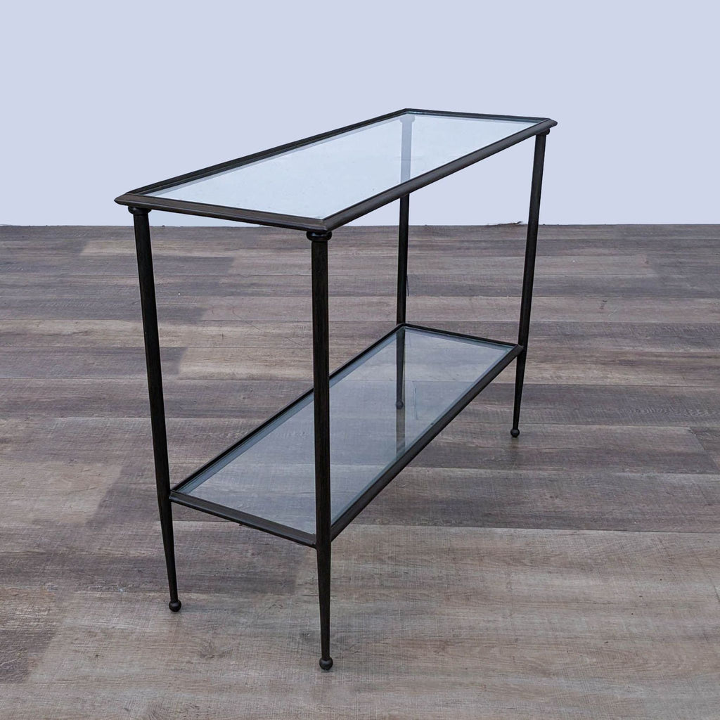 a black metal and glass side table with a glass shelf.