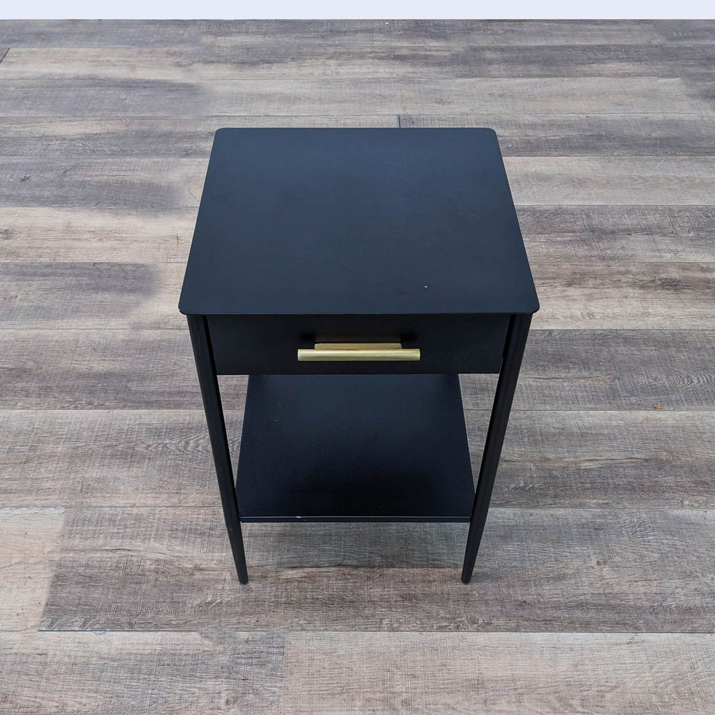 a black side table with a gold drawer.