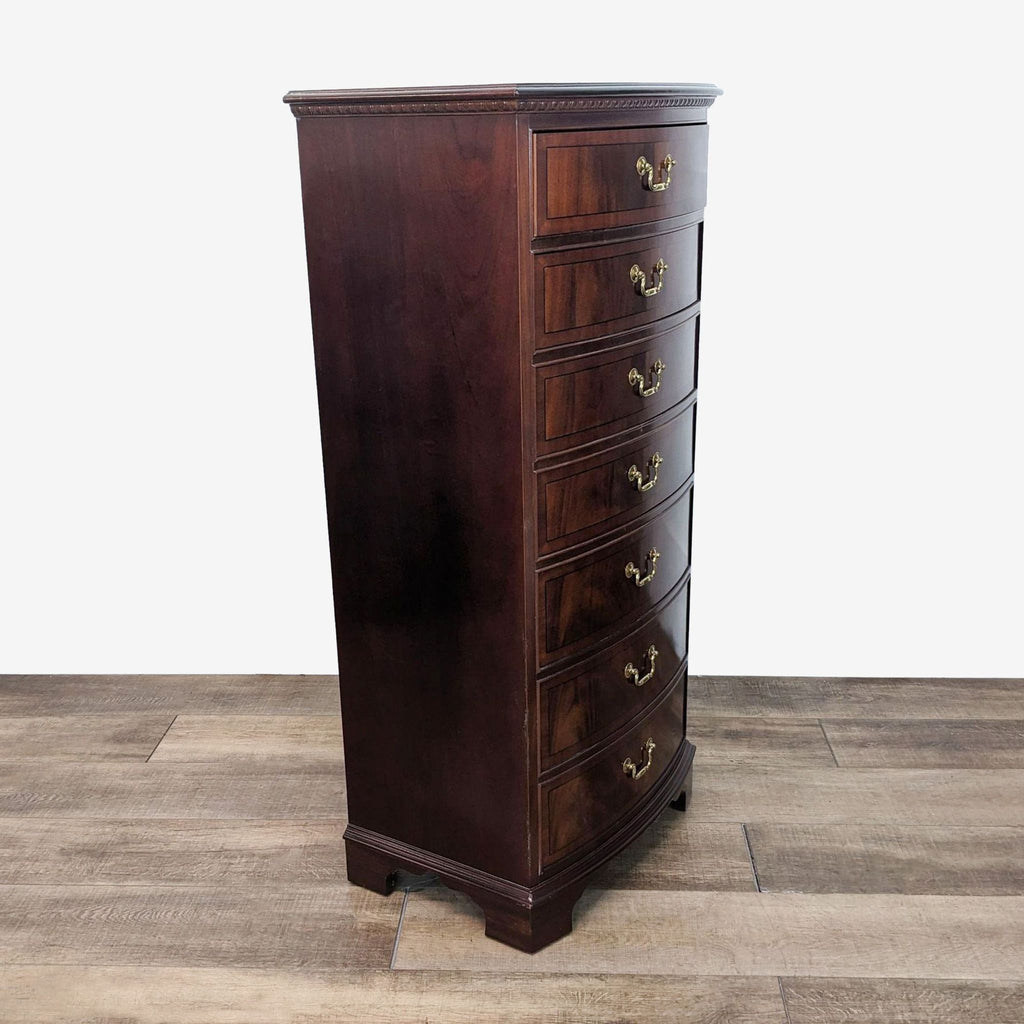 a tall, dark cherry wood tall chest of drawers with brass handles.