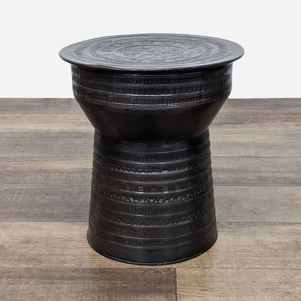 a black cast iron stool with a woven top.