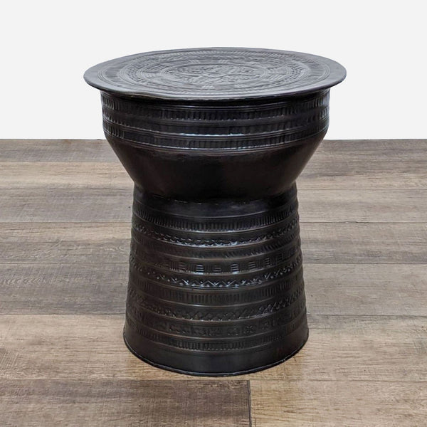 a black cast iron stool with a woven top.