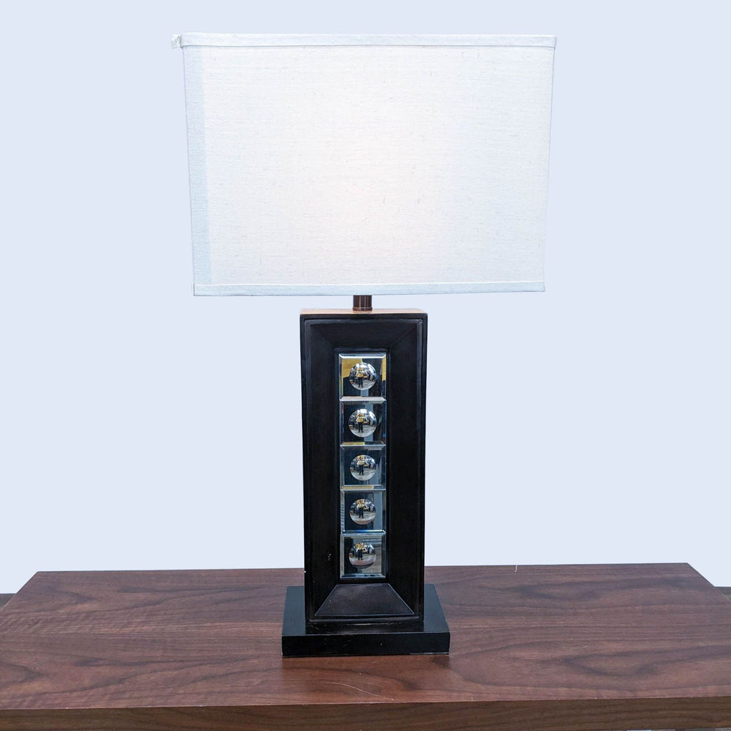 Reperch lamp with geometric base and white rectangular shade on wooden table.