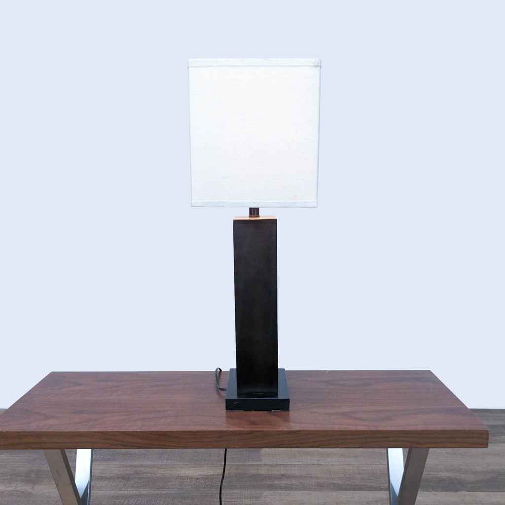 Side view of Reperch lamp featuring white shade and dark rectangular base on wood table.