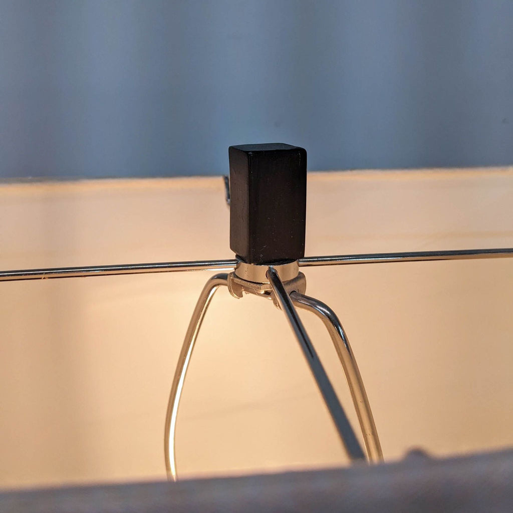Close-up of Reperch lamp's top, showing metal frame and shade finial.