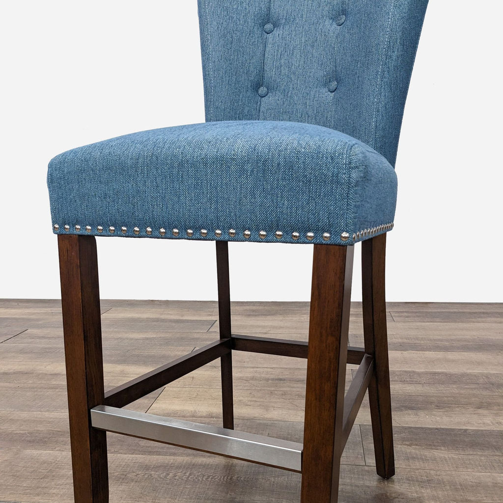 a blue denim bar stool with a wooden frame and metal legs.