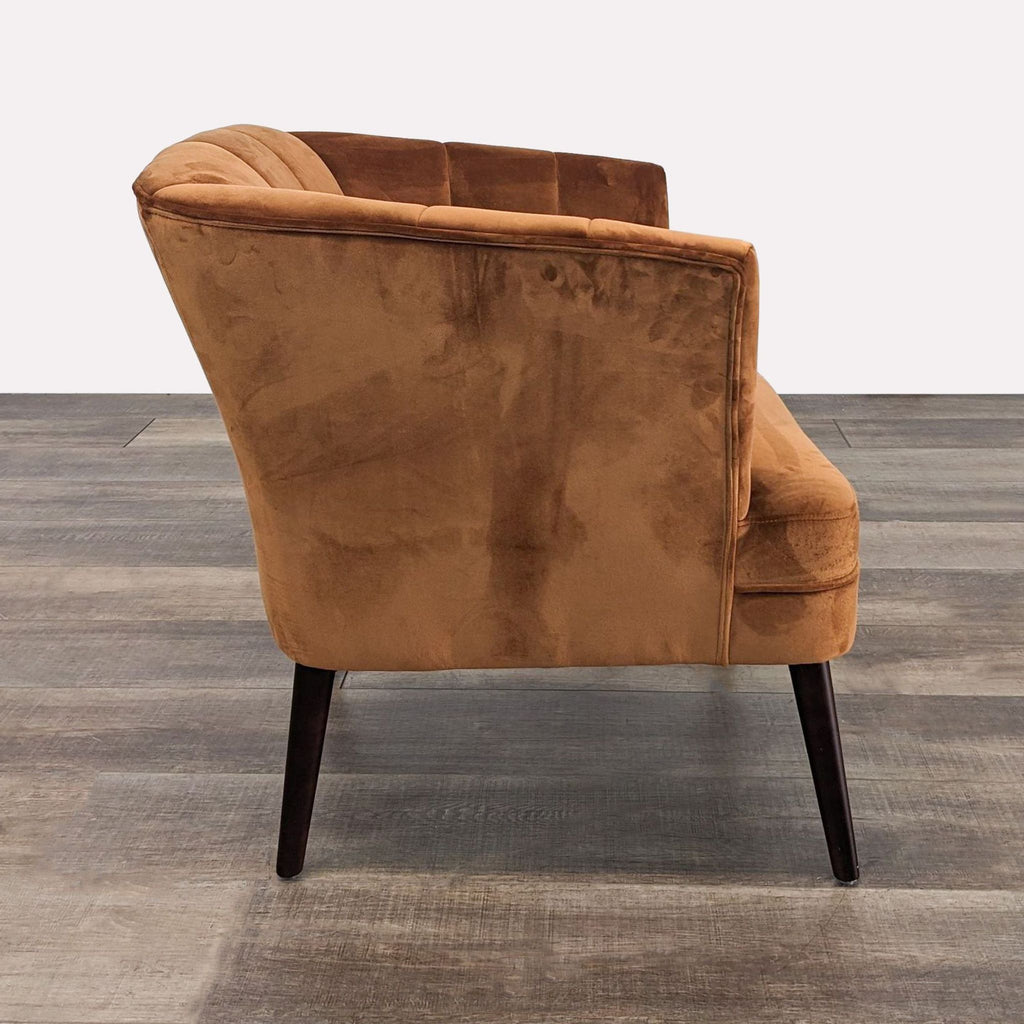 Side view of mid-century rust velvet chair featuring plush upholstery and sleek wood legs.