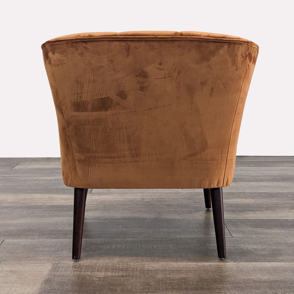 Back view of a rust velvet chair showcasing the curved back and wooden legs design.