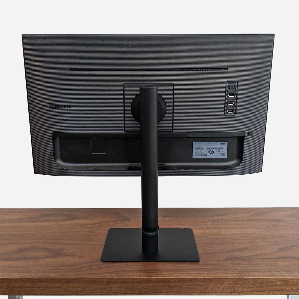 a black computer monitor on a wooden desk.