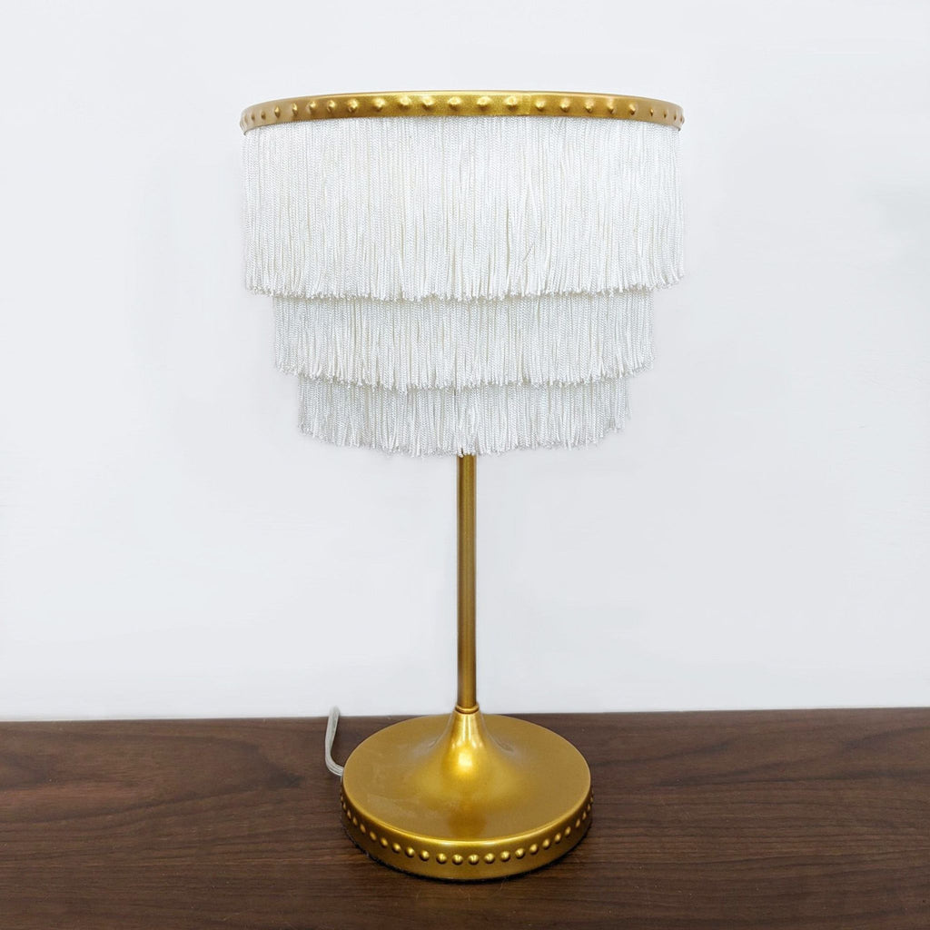 a vintage brass table lamp with white fringes.