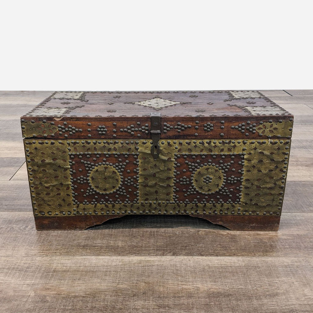 a small, rectangular, wooden chest with a decorative design.