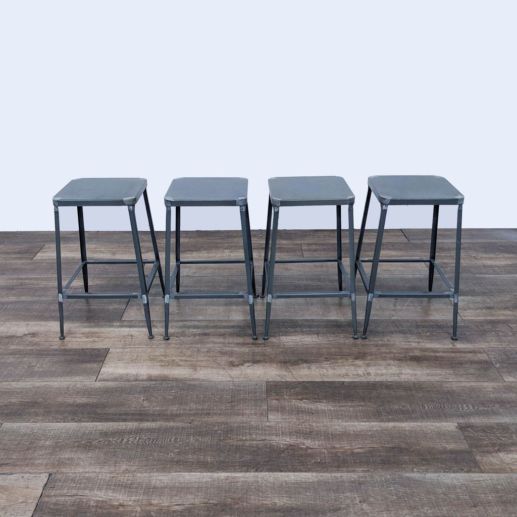 a set of four metal stools with glass top.