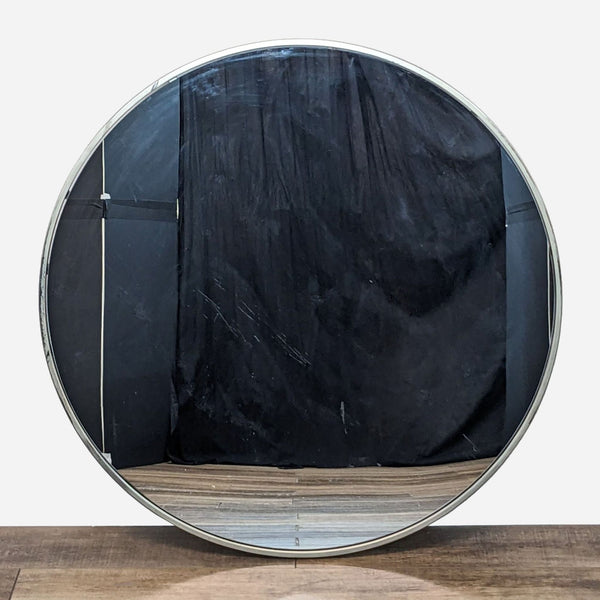 a large circular mirror with a black fabric covering it.